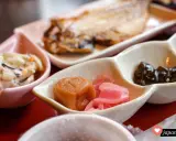 Ein traditionelles japanisches Frühstück mit gegrilltem Fisch, eingelegtem Gemüse und einer cremigen Beilage.