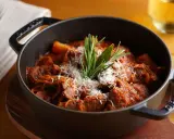 Herzhaftes italienisches Ragout in einem gusseisernen Topf, garniert mit Parmesan und Rosmarin.