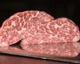 Zwei saftige Steaks vom Kobe Rind liegen auf einem metallischen Untergrund. Ihr auffälliges Marmormuster aus Fett und Fleisch verspricht ein einzigartiges Geschmackserlebnis.