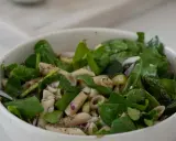 Ein frischer nudelsalat mit spargel, garniert mit Spinat und roten Zwiebeln, bereit zum Genießen.