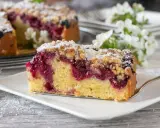 Ein saftiges Stück Streuselkuchen mit Marmelade und Puderzucker bestreut, bereit zum Genuss.
