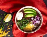 Herzhafter schwarze bohnen eintopf mit Avocado, Sauerrahm, Zwiebeln und Koriander. Ein Genuss für kalte Tage.