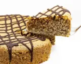 Ein Stück zuckerfreier Kuchen mit Schokoladenglasur wird aus einem Ganzen gehoben.