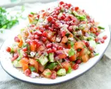 Frischer persischer Salat mit Granatapfel, Tomaten, Gurken und Kräutern, bestreut mit Sumach.
