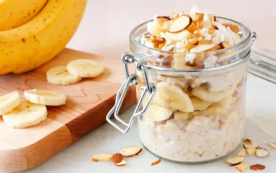 Gesunder Porridge mit Banane, Nüssen und Kokosraspeln im Glas. Perfekt für einen energiegeladenen Start in den Tag.