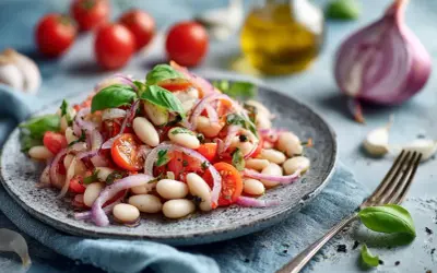 Ein frischer weisse bohnen salat mit Tomaten, roten Zwiebeln und Basilikum, garniert mit Olivenöl und Gewürzen.