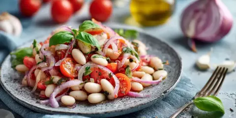 Ein frischer weisse bohnen salat mit Tomaten, roten Zwiebeln und Basilikum, garniert mit Olivenöl und Gewürzen.