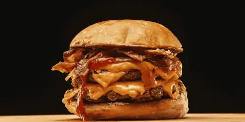 Ein saftiger Burger zubereiten: Doppelt Fleisch, geschmolzener Käse, knuspriger Bacon und eine köstliche Sauce.