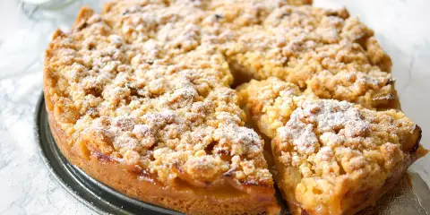 Omas weltbester Apfelkuchen, goldbraun gebacken mit knuspriger Streuseldecke und saftigen Äpfeln. Ein Stück Glück!