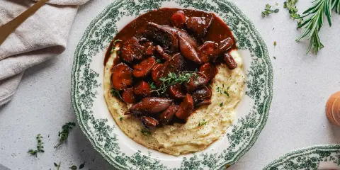 Herzhaftes Pilz-Bourguignon auf cremigem Kartoffelpüree, garniert mit frischen Kräutern. Ein Genuss für jeden Gaumen.