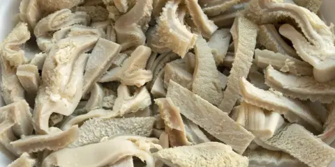 Ein Haufen geschnittener Kutteln, die für die Zubereitung von Gerichten wie "was sind Kutteln" vorbereitet werden.