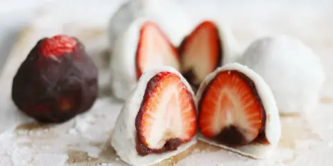 Erdbeeren-Wagashi-Rezept: Süße Mochi-Bällchen mit frischen Erdbeeren und roter Bohnenpaste, bestäubt mit Puderzucker.
