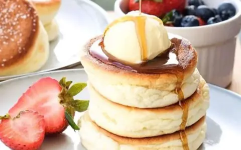 Fluffige japanische Pancakes mit einer Kugel Eis, Sirup und frischen Beeren. Ein Traum zum Frühstück!