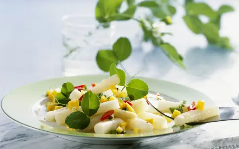 Ein frischer Spargel Mango Salat mit roten Paprikastückchen und grünen Blättern, garniert mit zarten Sprossen.