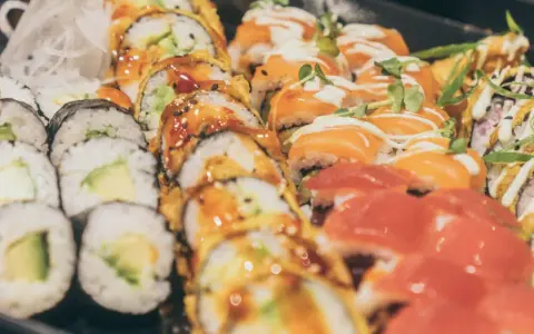 Vielfalt an Sushi-Rollen mit Lachs, Avocado und frischen Kräutern. Eine Frage, wie gesund ist Sushi, lässt sich hier nicht pauschal beantworten.