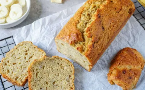 Goldbraunes Bananenbrot, frisch gebacken, mit geschnittenen Scheiben daneben. Ein gesundes Bananenbrot Rezept zum Genießen.