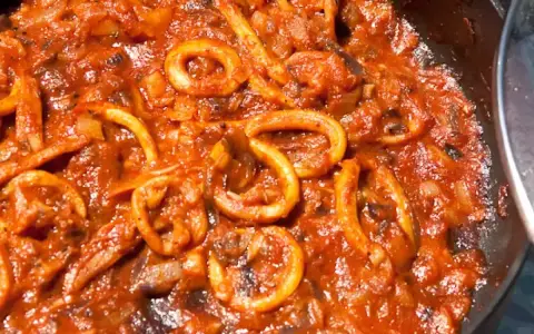 Sepia-farbene Tintenfischringe in einer würzigen Tomatensauce, perfekt für ein mediterranes sepia rezept.