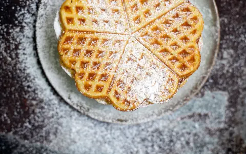 Herzförmige Waffeln mit Puderzucker bestreut, serviert auf einem Teller. Ein Genuss, der an Sommer und Kokosmilch erinnert.