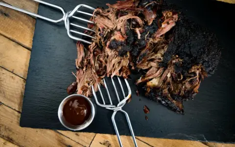 Saftiges pulled beef mit dunkler Kruste, serviert mit BBQ-Sauce.