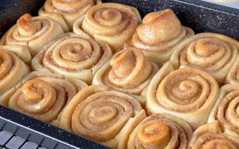 Frisch gebackene, fluffige Zimtschnecken in einer Backform. Sie duften nach Zimt und Zucker und sind bereit zum Genießen.
