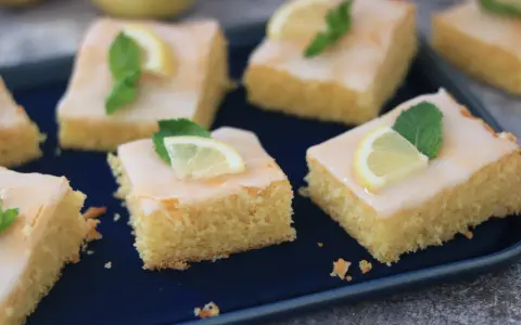 Saftige Kuchenstücke mit Zitronenguss, garniert mit Zitronenspalten und Minze. Ein Genuss, der nach dem besten zitronenkuchen der welt schmeckt.