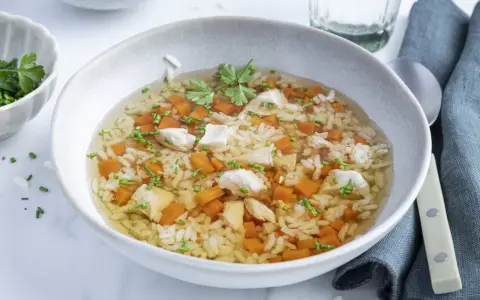 Eine wärmende Reissuppe mit Huhn, Karottenwürfeln und frischen Kräutern, perfekt für kalte Tage.