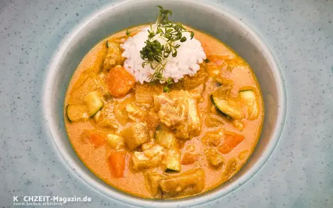 Ein cremiger Lachs Curry mit Reis und Gemüse, garniert mit frischen Sprossen.