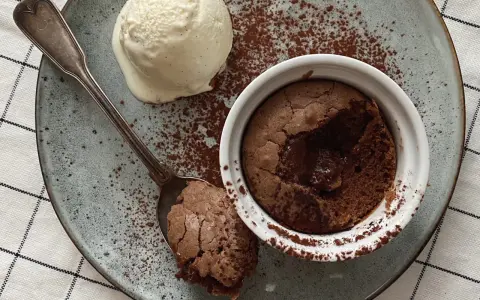 Ein warmer, flüssiger Kern im Moelleux au chocolat, serviert mit einer Kugel Vanilleeis und Kakaopulver.