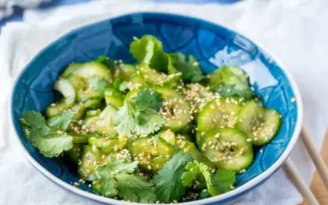 Erfrischender Gurkensalat asiatisch, garniert mit Koriander und Sesam. Perfekt als leichte Beilage.