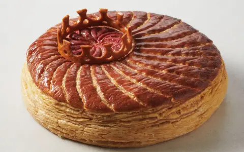 Goldbraune Galette des Rois mit einer Krone aus Blätterteig, die die traditionelle Epiphanie-Feier symbolisiert.