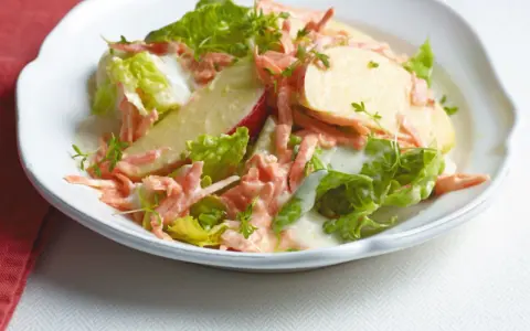 Erfrischender karotten apfel-salat mit joghurt und knackigem Salat, garniert mit Kresse.