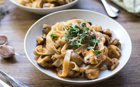 Herzhafte Pasta mit Pilzsauce, ein italienischer Genuss, garniert mit frischen Sprossen.