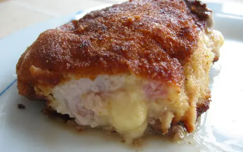 Ein goldbraunes Cordon Bleu, das innen mit geschmolzenem Käse und Schinken gefüllt ist. Seine Herkunft ist oft umstritten, aber der Geschmack ist unbestritten.