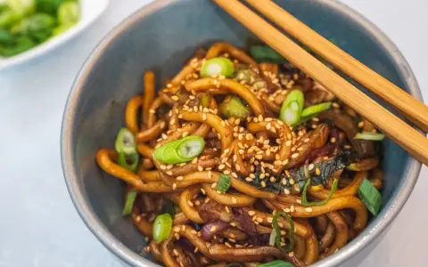 Schüssel mit Udon-Nudeln, garniert mit Frühlingszwiebeln und Sesam. Diese dicken, zähen Nudeln sind ein Klassiker der japanischen Küche.