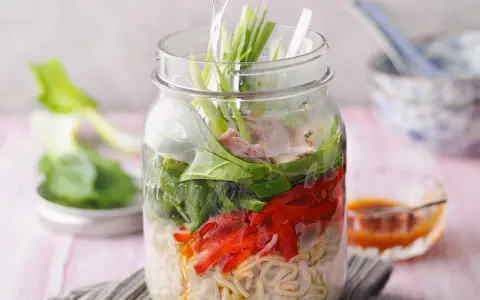 Eine köstliche pak choi suppe in einem Glas, geschichtet mit Nudeln, Gemüse und Fleisch.