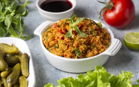 Frischer Bulgursalat mit Tomaten, Kräutern und Minze, serviert mit Gurken und Limette. Das beste bulgursalat rezept für einen leichten Genuss.