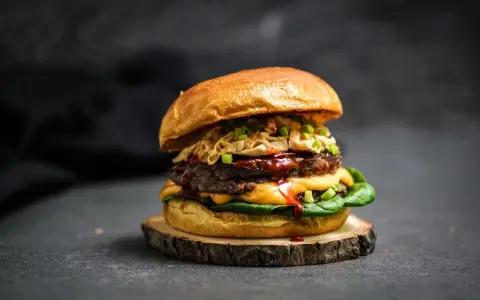 Ein saftiger koreanischer Burger mit doppeltem Patty, Käse, knackigem Krautsalat und Frühlingszwiebeln auf einem rustikalen Holzbrett.