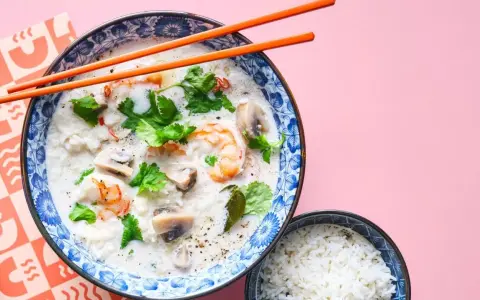 Khao tom, eine cremige Reissuppe mit Garnelen, Pilzen und Koriander, wird mit einem Schälchen Reis serviert.