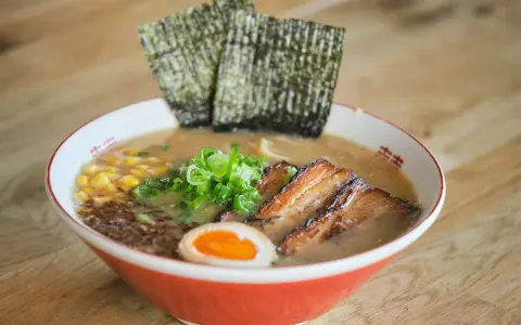 Herzhaftes Miso Ramen mit zartem Schweinebauch, Mais, Frühlingszwiebeln, Ei und Nori-Algen.