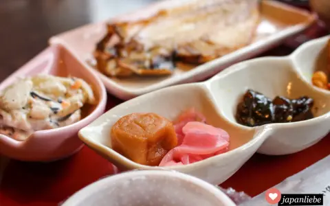 Ein traditionelles japanisches Frühstück mit gegrilltem Fisch, eingelegtem Gemüse und einer cremigen Beilage.
