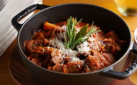 Herzhaftes italienisches Ragout in einem gusseisernen Topf, garniert mit Parmesan und Rosmarin.