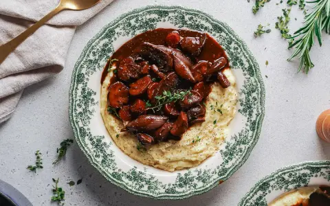 Herzhaftes Pilz-Bourguignon auf cremigem Kartoffelpüree, garniert mit frischen Kräutern. Ein Genuss für jeden Gaumen.