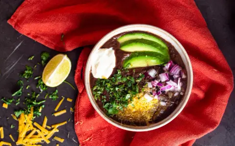 Herzhafter schwarze bohnen eintopf mit Avocado, Sauerrahm, Zwiebeln und Koriander. Ein Genuss für kalte Tage.
