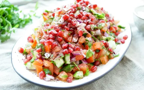 Frischer persischer Salat mit Granatapfel, Tomaten, Gurken und Kräutern, bestreut mit Sumach.