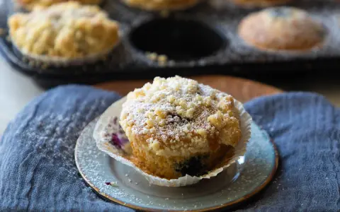 Saftige Blaubeermuffins mit Joghurt und Streuseln, bestäubt mit Puderzucker. Ein Genuss für jeden Kaffeetisch.