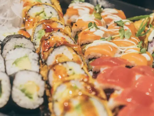 Vielfalt an Sushi-Rollen mit Lachs, Avocado und frischen Kräutern. Eine Frage, wie gesund ist Sushi, lässt sich hier nicht pauschal beantworten.