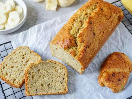 Goldbraunes Bananenbrot, frisch gebacken, mit geschnittenen Scheiben daneben. Ein gesundes Bananenbrot Rezept zum Genießen.