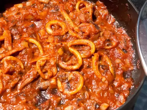 Sepia-farbene Tintenfischringe in einer würzigen Tomatensauce, perfekt für ein mediterranes sepia rezept.