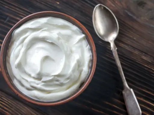 Schüssel mit cremiger Joghurt-Textur, eine tolle Alternative, wenn man fragt, was kann man statt Creme Fraiche nehmen. Daneben eine Löffel.