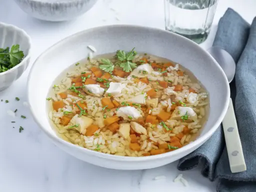 Eine wärmende Reissuppe mit Huhn, Karottenwürfeln und frischen Kräutern, perfekt für kalte Tage.